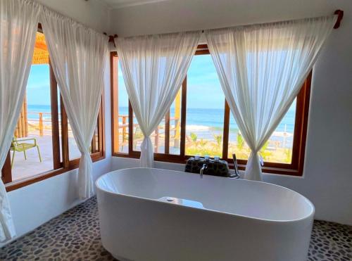 a white bath tub in a room with windows at Casa GAIA - Punta Sal in Canoas De Punta Sal