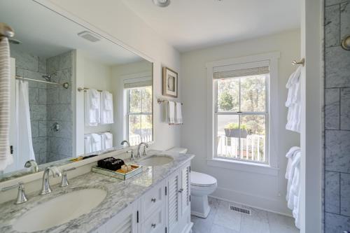 a white bathroom with two sinks and a toilet at Beach Cottage with Fire Pit Less Than 6 Mi to Nags Head! in Manteo