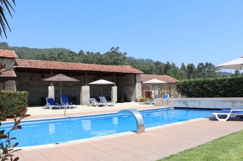 a swimming pool in front of a house with chairs and umbrellas at Quinta da Presa in Vermoim
