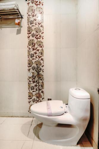 a bathroom with a white toilet and a curtain at Hotel Grand Shiva Haridwar in Haridwār