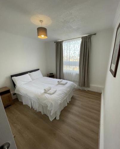 a bedroom with a white bed and a window at Great Location 4 bedroom in London