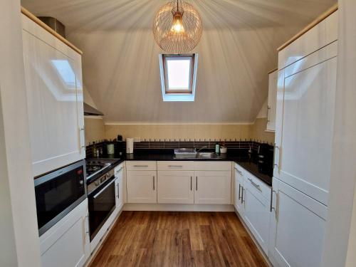 a kitchen with white cabinets and a chandelier at Trendy Luxury Serviced Apartment next to City Centre with Free Parking - Contractors & Relocators in Coventry