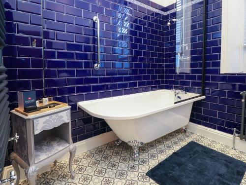 baño de azulejos azules con bañera blanca en Ismay Dining Room Suite - Titanic Interest, en Crosby