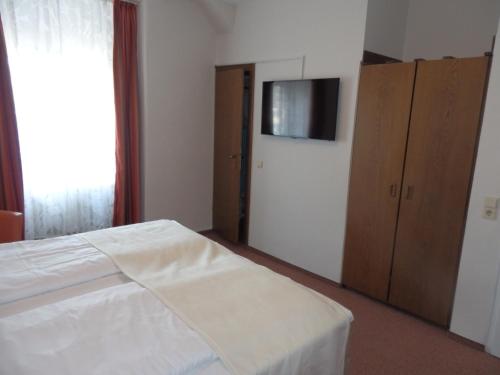 a bedroom with a bed and a cabinet and a television at Hotel Rheinischer Hof in Bad Breisig