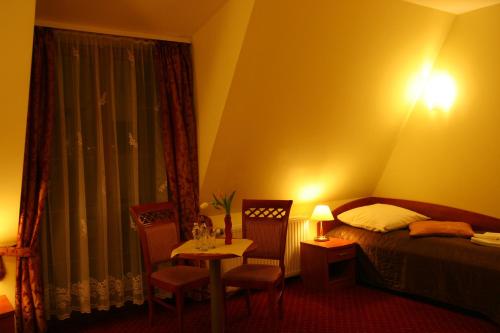 a hotel room with a bed and a table and chairs at Hotel Karolinka in Gogolin