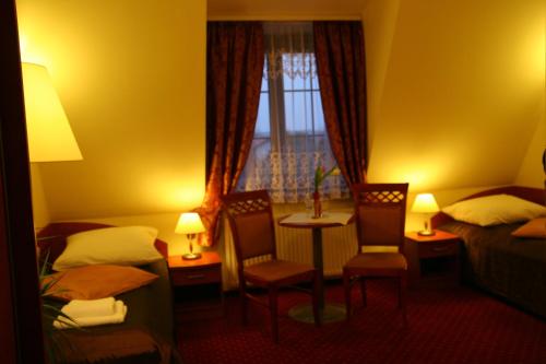 Habitación de hotel con 2 camas, mesa y sillas en Hotel Karolinka, en Gogolin