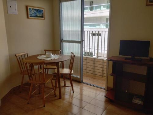 a dining room with a table and chairs and a television at Apto Aconchegante Praia Grande in Praia Grande