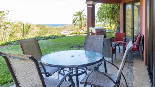 una mesa y sillas en un porche con parrilla en Bougainvillea 2102 Luxury Apartment - Reserva Conchal, en Playa Conchal