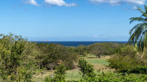 una vista de un campo de golf con el océano en el fondo en Bougainvillea 2102 Luxury Apartment - Reserva Conchal, en Playa Conchal