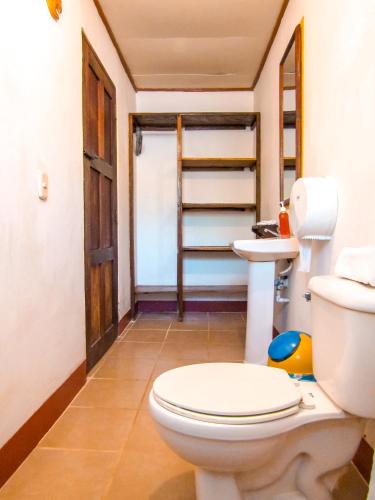 a bathroom with a white toilet and a door at Hotel Restaurante Spa La Barca de Oro in Las Peñitas