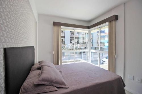 sypialnia z łóżkiem i dużym oknem w obiekcie Residencial Frederico w mieście Bombinhas