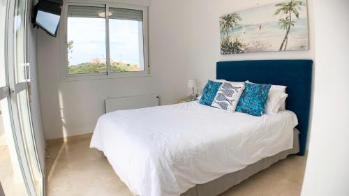 a bedroom with a bed with blue and white pillows at Villa Bendex Estepona Costa Del Sol in Estepona