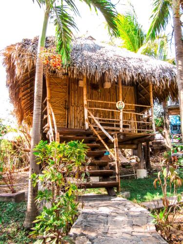 a small hut with a thatched roof and palm trees at Hotel Restaurante Spa La Barca de Oro in Las Peñitas