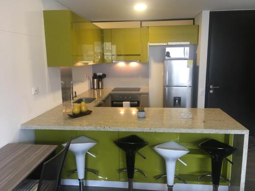 a kitchen with yellow and green cabinets and a counter with stools at Enjoy In Bogotá in Bogotá