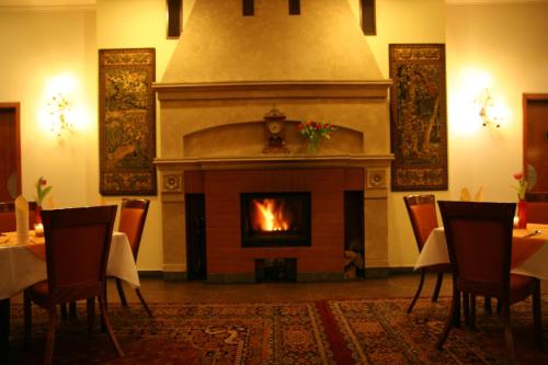 a fireplace in a dining room with tables and chairs at Hotel Karolinka in Gogolin