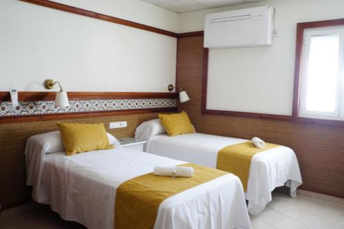 Habitación de hotel con 2 camas y ventana en Hostal La Conileña, en Conil de la Frontera