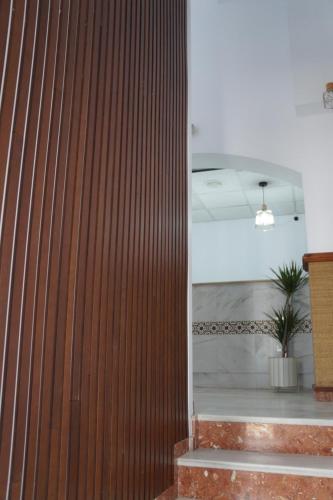 a wooden wall in a lobby with a plant at Hostal La Conileña in Conil de la Frontera