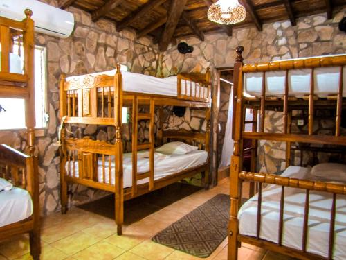 a room with four bunk beds in a stone wall at Hotel Restaurante Spa La Barca de Oro in Las Peñitas