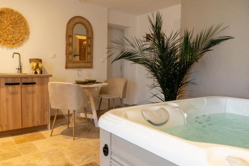 uma casa de banho com uma banheira com uma mesa e uma sala de jantar em L’Amazonie Gite Spa em Beutin