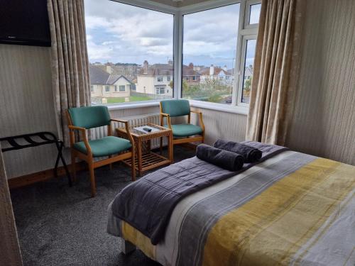 - une chambre avec deux chaises, un lit et une fenêtre dans l'établissement Brae-Mar B&B, à Portrush