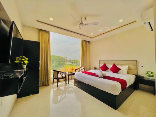 a bedroom with a bed and a table and a window at "Hotel The Lycoris" Near Bus Stand ZIRAKPUR on AMBALA HIGHWAY in Zirakpur