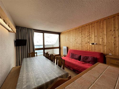 レ・メニュアールにあるAppartement Les Menuires, 3 pièces, 8 personnes - FR-1-452-171のテーブルと赤いベッドが備わる客室です。