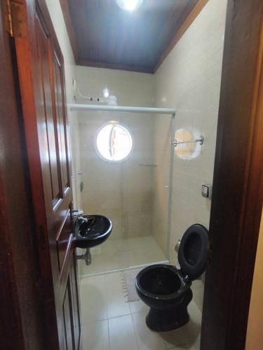 a bathroom with a black toilet and a sink at Pousada Taquinha Paraty in Paraty