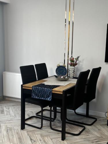 mesa de comedor con sillas negras y lámpara en Apartament Elisabeth BLUE I, en Pogórze