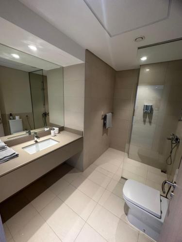 ein Badezimmer mit einem Waschbecken, einem WC und einem Spiegel in der Unterkunft Modern Apartment in Racing Paradise: Close to Ferrari World & F1 Track in Abu Dhabi