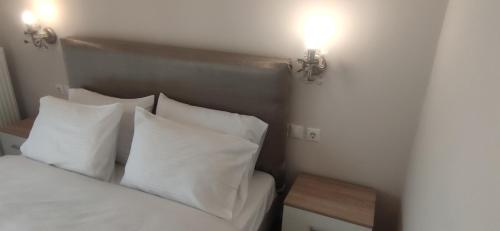 a bedroom with a bed with white pillows and two lights at Η πέρλα της λίμνης/ The lake's pearl in Ioannina