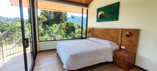 a bedroom with a bed and a large window at Balcón de Mindo in Mindo