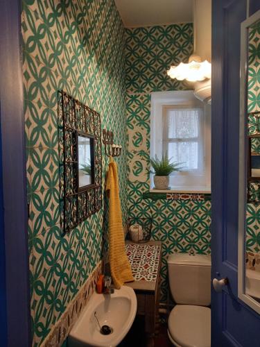 La salle de bains est pourvue de papier peint vert, d'un lavabo et d'un miroir. dans l'établissement Biarritz , plage Côte des Basques, Beaurivage, à Biarritz