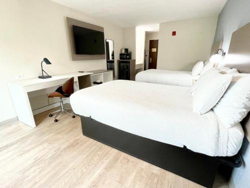 a hotel room with two beds and a desk and a television at Days Inn by Wyndham Arlington in Arlington