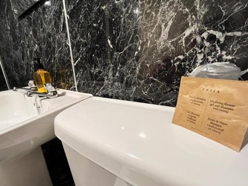 un bagno con lavandino e servizi igienici bianchi con un cartello sopra di Buccleuch Arms Hotel a Moffat