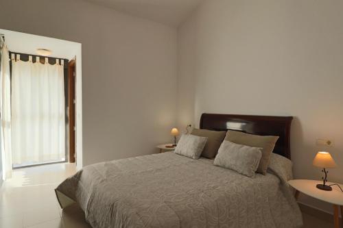 a bedroom with a bed with two lamps and a window at Exclusivo Adosado en Punta Coral El Rompido in El Rompido