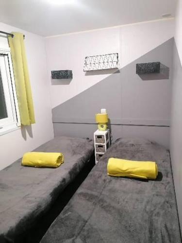 deux lits dans une chambre avec des oreillers jaunes dans l'établissement Mobil-Home Cosy Climatisé 3 chambres, à Vic-la-Gardiole