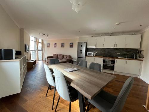 a kitchen and living room with a wooden table and chairs at Ultra-Luxury City centre 2 bed apartment, with FREE parking in Cardiff