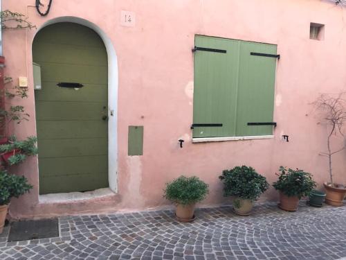a pink building with two green doors and potted plants at DUPLEX EN PLEIN COEUR DU VILLAGE in Cassis