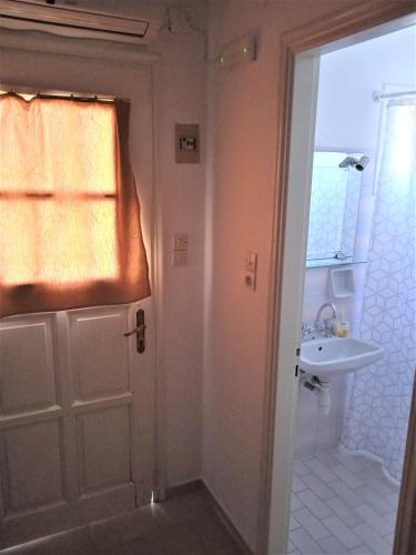 a bathroom with a white door and a sink at Anthemis Studios in Skala Eresou