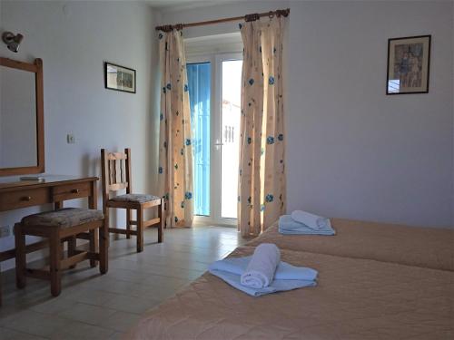 a bedroom with a bed and a desk and a window at Anthemis Studios in Skala Eresou