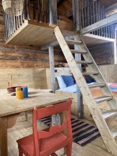 a loft bed with a wooden table and a ladder at Sauefjøset - Idyllisk gardstun fra 1800-tallet in Skjåk