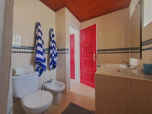 łazienka z białą toaletą i czerwonymi drzwiami w obiekcie A casa da Laranjeira w mieście Vale Covo