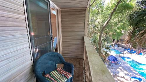 a balcony with a chair next to a swimming pool at Villas by The Sea Three Bedroom Apartment in Jekyll Island