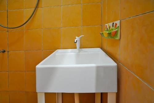ein weißes Waschbecken im Badezimmer mit orangefarbener Wand in der Unterkunft OYO 92377 Wisma Melyro Syariah 