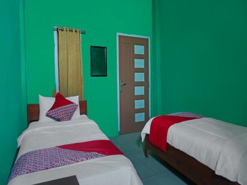 2 Betten in einem Zimmer mit grünen Wänden in der Unterkunft OYO 92377 Wisma Melyro Syariah 