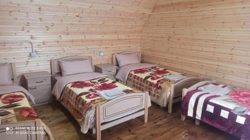 3 camas en una habitación con paredes de madera en Hotel-Restorant Pepushaj en Shkodër