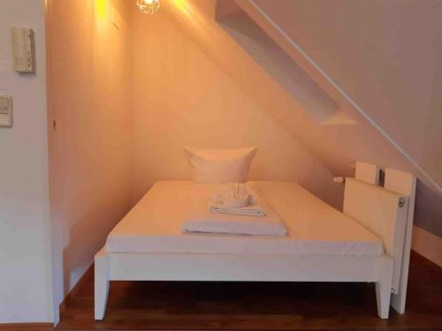 a small white bed in a room with stairs at Apartment Blattgold in Schwabach