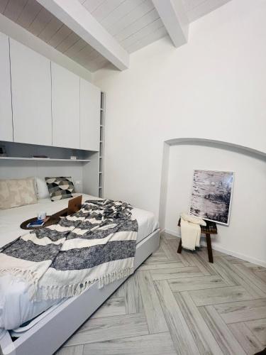 a white bedroom with a bed and a wooden floor at [Ferrara Centro - SABI APT] in Ferrara