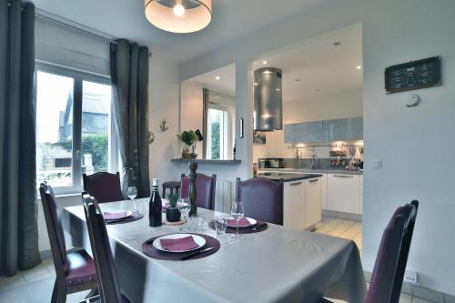 une table de salle à manger avec des chaises et une cuisine dans l'établissement La Maison des Rivages - Proche plages et Golf, à Saint-Briac-sur-Mer