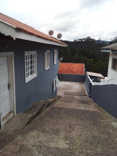 ein blaues Haus mit einer weißen Tür und einer Einfahrt in der Unterkunft Cantinho aconchegante in Campos do Jordão